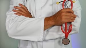 doctor in white jacket holding stethoscope